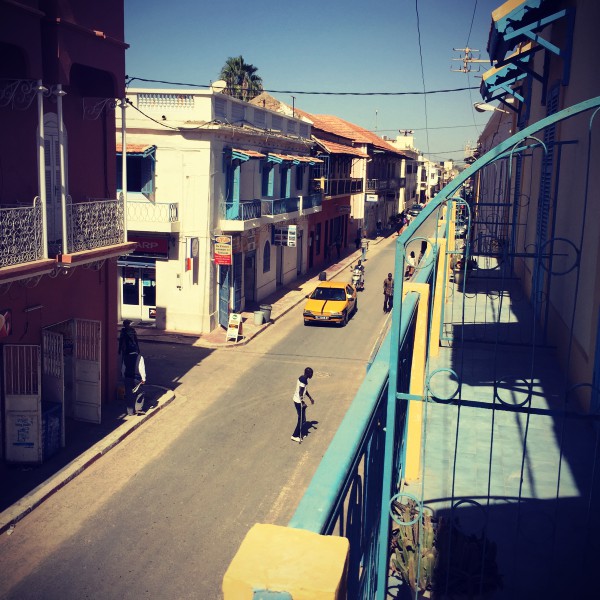 Une rue de Saint-Louis depuis mon balcon, des gens dans la rue et un taxi jaune #Off2Africa 19 Saint-Louis Sénégal © Gilles Denizot 2016