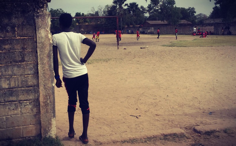 Un jeune homme au tshirt blanc regarde un match de football #Off2Africa 48 Ziguinchor Casamance Sénégal © Gilles Denizot 2017