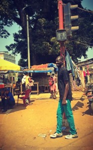 Un homme vêtu d'un pantalon vert attend sous un passage à piéton vert #Off2Africa 67 Conakry Guinée © Gilles Denizot 2017