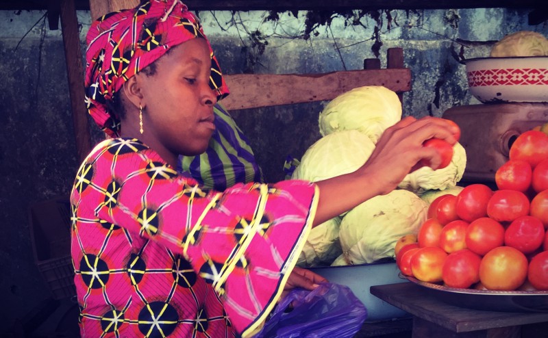 Une femme vêtue d'un boubou rose dispose des tomates sur un plat #Off2Africa 70 Conakry Guinée © Gilles Denizot 2017