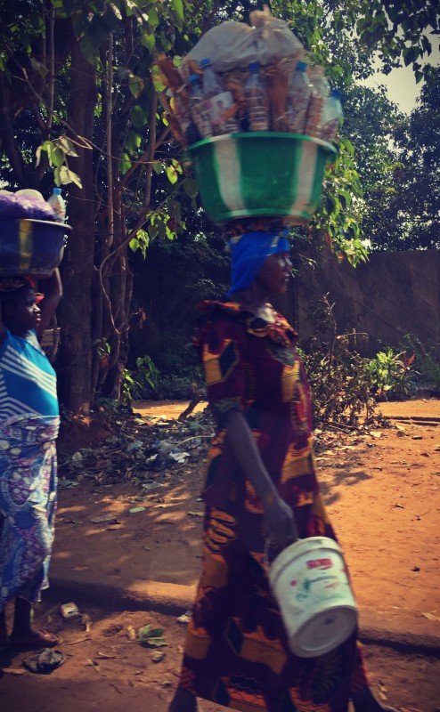 Deux femmes portant sur la tête des bidons énormes remplis de marchandises #Off2Africa 78 Conakry Guinée © Gilles Denizot 2017