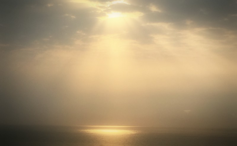 Le soleil brille à travers les nuages et dépose une trace de lumière sur l'océan