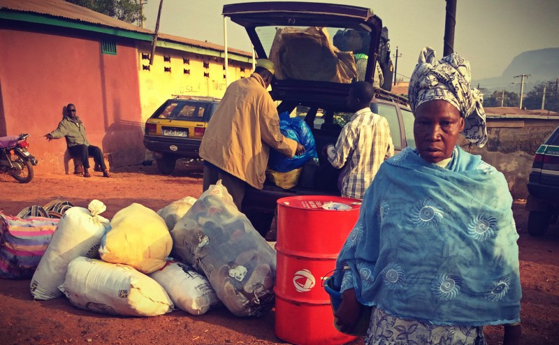 On charge un taxi-brousse de multiples sacs tandis qu'une maman au boubou passe son chemin #Off2Africa 83 Kankan Guinée © Gilles Denizot 2017