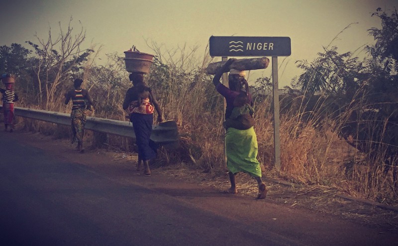 Traversée du Niger, des femmes marchent en file indienne, en portant des charges sur la tête et un enfant dans le dos v