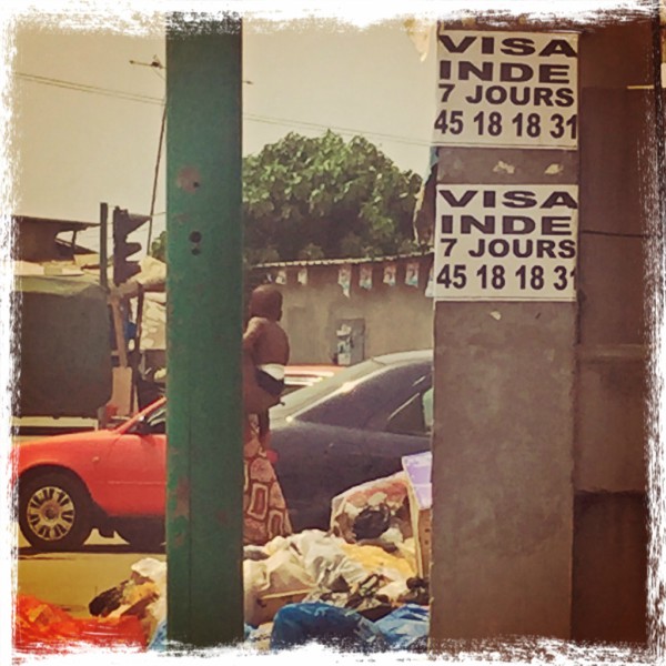 Dans une rue, autour de piles d'ordures, des publicités pour de Visa INDE en 7 jours #Off2Africa 97 Abidjan Côte d'Ivoire © Gilles Denizot 2017