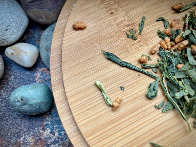 Des galets, une planche en bois avec des feuilles de thé vert et des grains de riz grillé © Gilles Denizot 2023