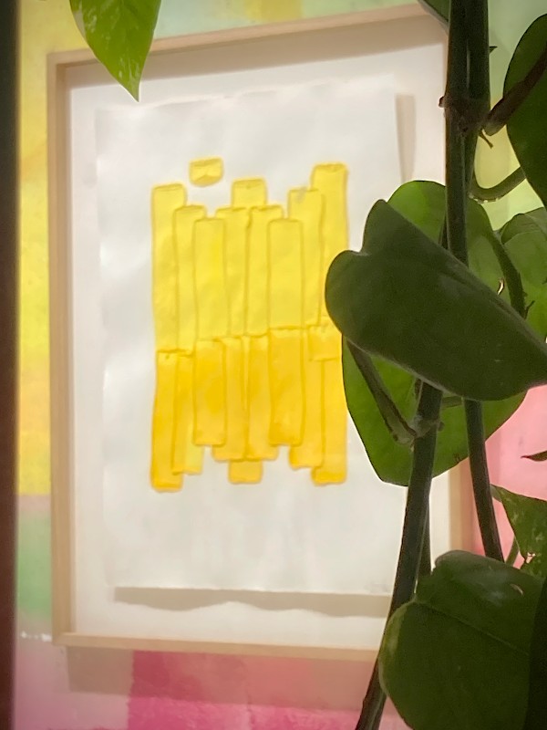 Un tableau dans les tons jaunes. Sur la droite, une plante verte s'immisce dans le cadre #HolaBCN thankyouforthehappy © Gilles Denizot 2024