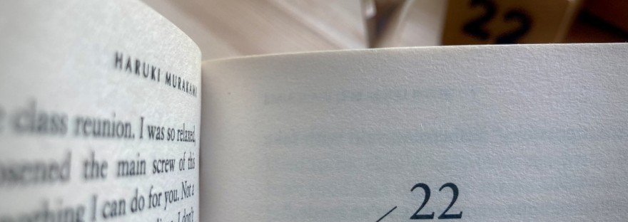 Un livre de Haruki Murakami ouvert au chapitre 22. En second plan, une coupe de cava et un cube qui indique 22 #HolaBCN Galaxie cinq sept © Gilles Denizot 2024