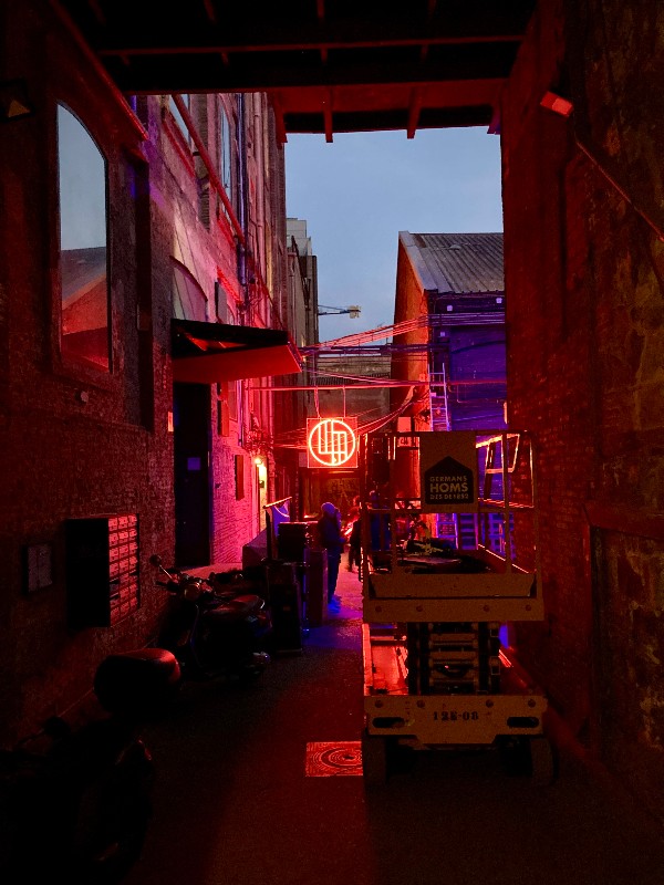 L'entrée d'un immeuble, encombrée, dans une lumière néon rouge et violacée #HolaBarcelona février 2023 © Gilles Denizot