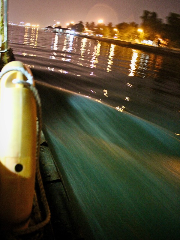 Un bateau sur l'eau, des lumières brillent dans la nuit #NoVisa Amour-fleuve © Gilles Denizot 2024