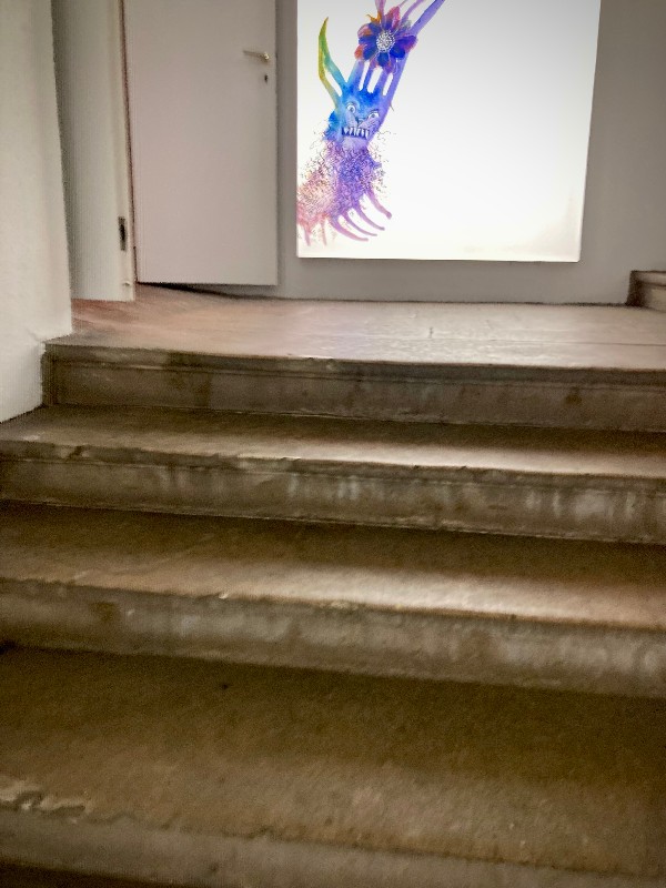 Les marches d'un escalier de pierre aboutissent à une figurine ricanante en couleurs ©GD24 #HolaBCN Pluie d'idées
